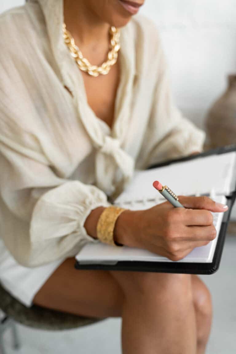 A woman sitting in a chair with a pen and notepad
