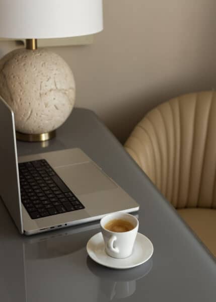 A laptop and a cup of coffee sit on a desk