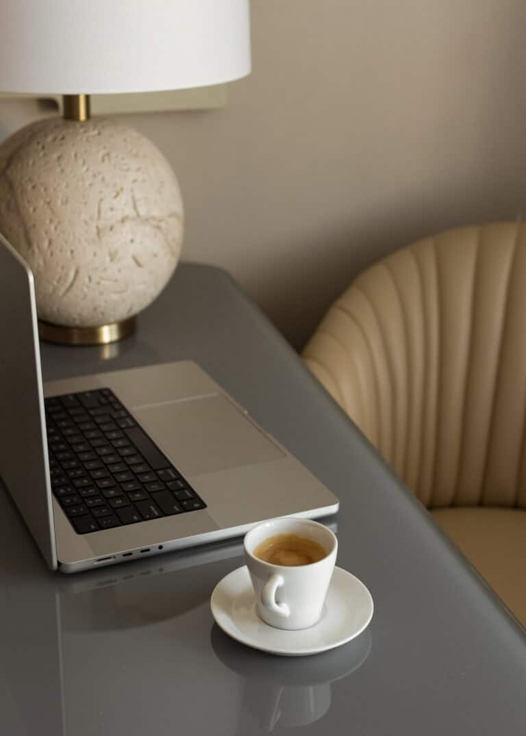 A laptop and a cup of coffee sit on a desk