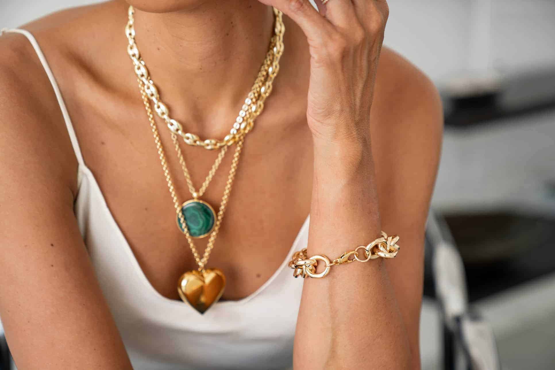 Luxueuze gouden sieraden waaronder kettingen met mooie edelstenen en een schakelarmband, perfect voor een stijlvolle look.