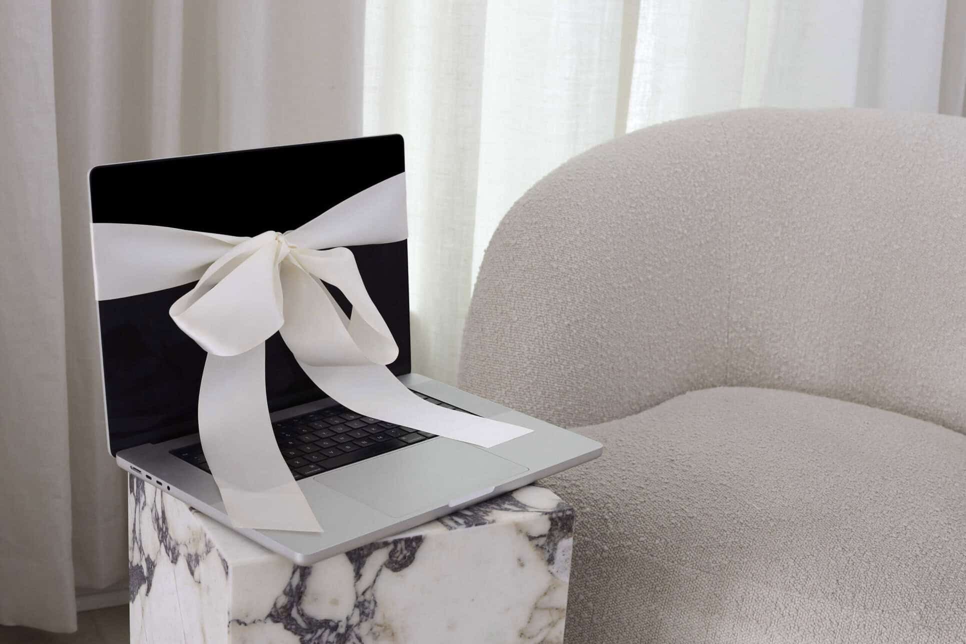 A laptop with a bow on it sitting on a chair